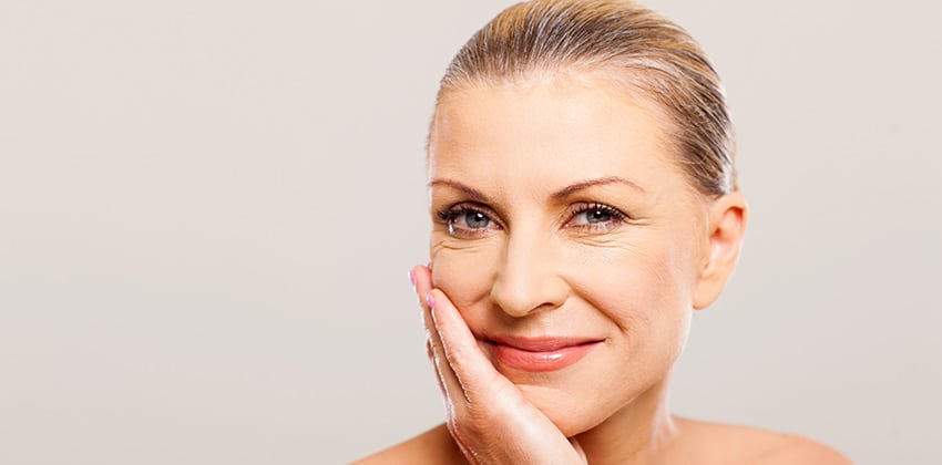 banner image of a middle aged woman resting her face against her hand and smiling