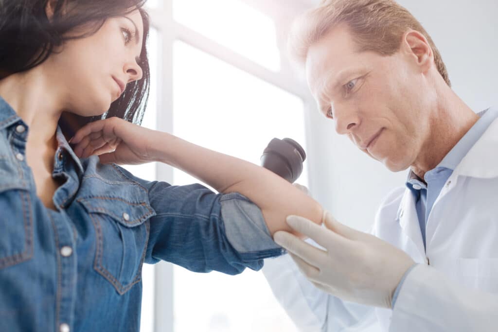 A doctor checking for signs of skin cancer on a patient’s arm